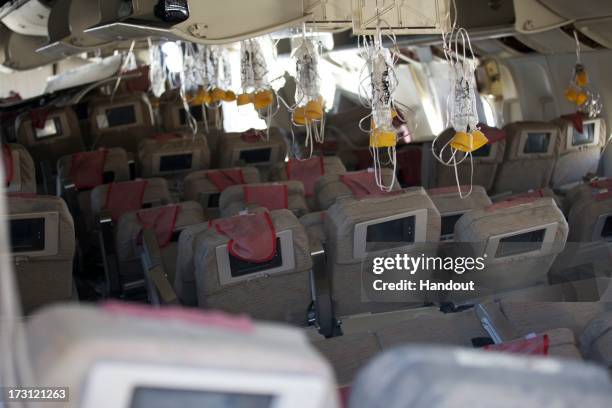 In this handout photo provided by the National Transportation Safety Board, oxygen masks hang from the ceiling in the cabin interior of Asiana...