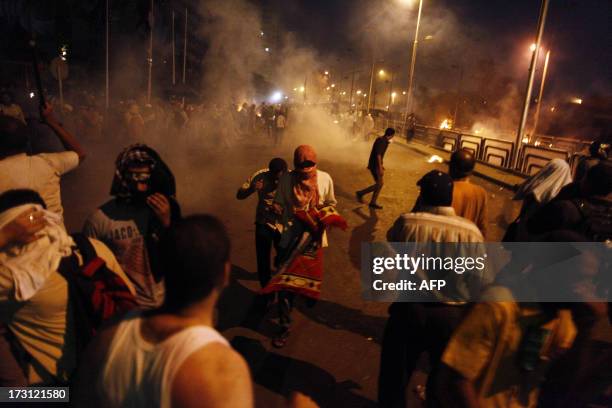 People run for cover as security forces fire tear gas after shooting to disperse Islamist supporters of ousted president Mohamed Morsi outside the...