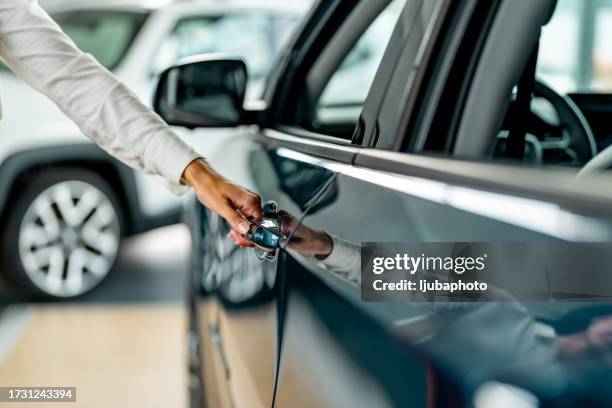 woman is opening the door of a new car. - car door stock pictures, royalty-free photos & images