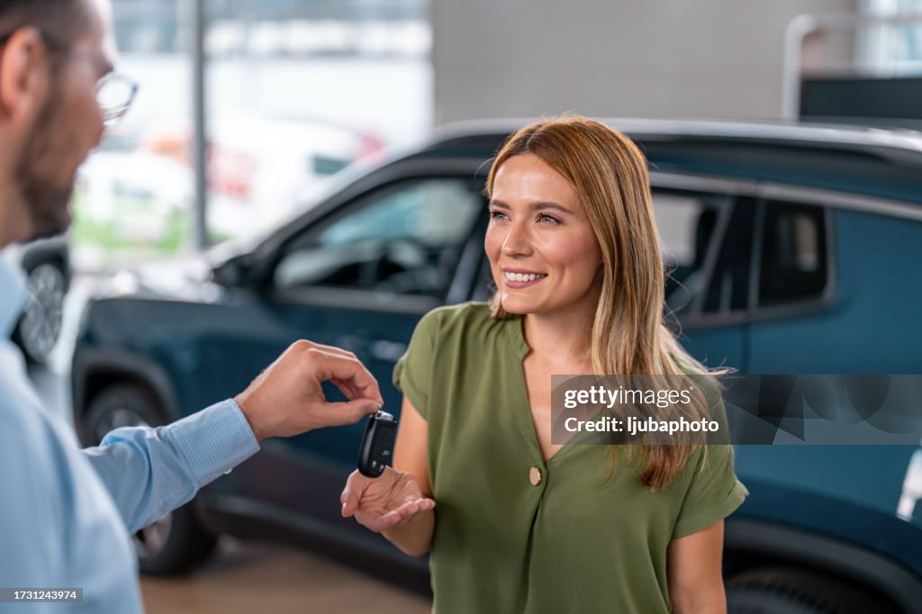 Autohändler gibt Schlüssel für ein neues Auto an eine Frau