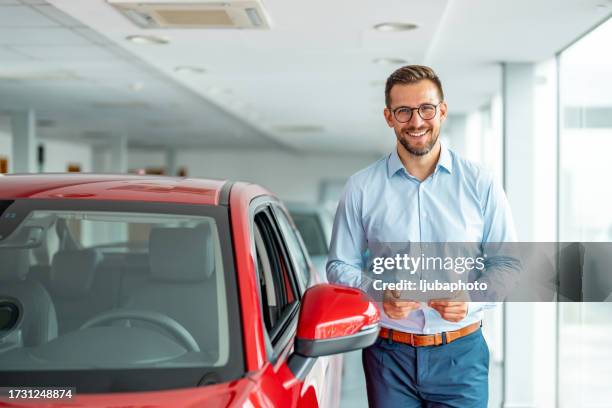 happy businessman choosing a car in a showroom. - autoverkoper stockfoto's en -beelden