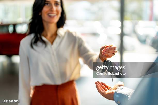 la donna sorridente sta dando la chiave dell'automobile a un cliente maschio. - chiave dellautomobile foto e immagini stock