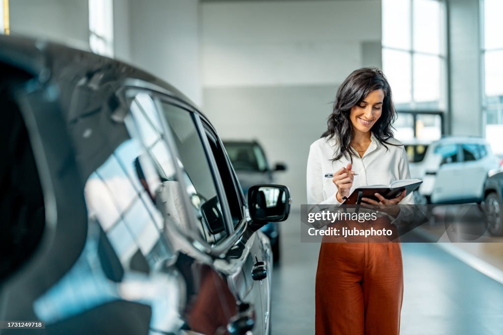 Smiling saleswoman working at a car dealership