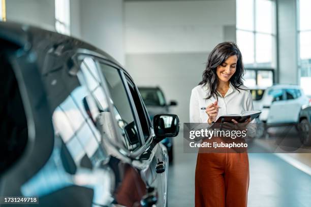 smiling saleswoman working at a car dealership - autodealer stockfoto's en -beelden
