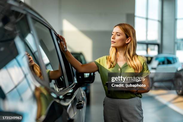 female car salesperson holding documents in a showroom. - car rental stock pictures, royalty-free photos & images