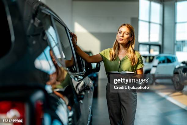 saleswoman taking notes while looking a car in a showroom. - selling stock pictures, royalty-free photos & images