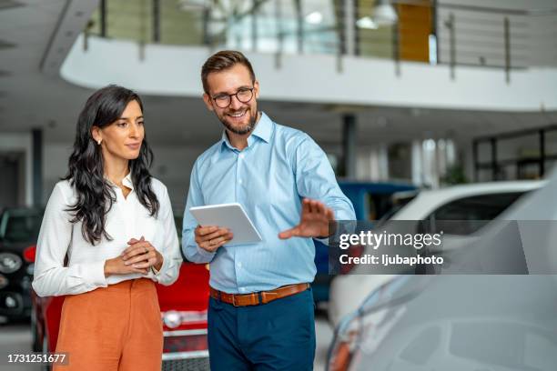 salesman helping the female customer to choose a new car - car salesperson stock pictures, royalty-free photos & images