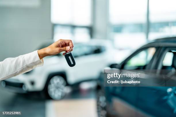 car salesperson giving the keys of a new car at the dealership - car display background stock pictures, royalty-free photos & images