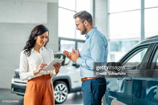 cheerful car dealership customer talking to auto sales consultant - autodealer stockfoto's en -beelden
