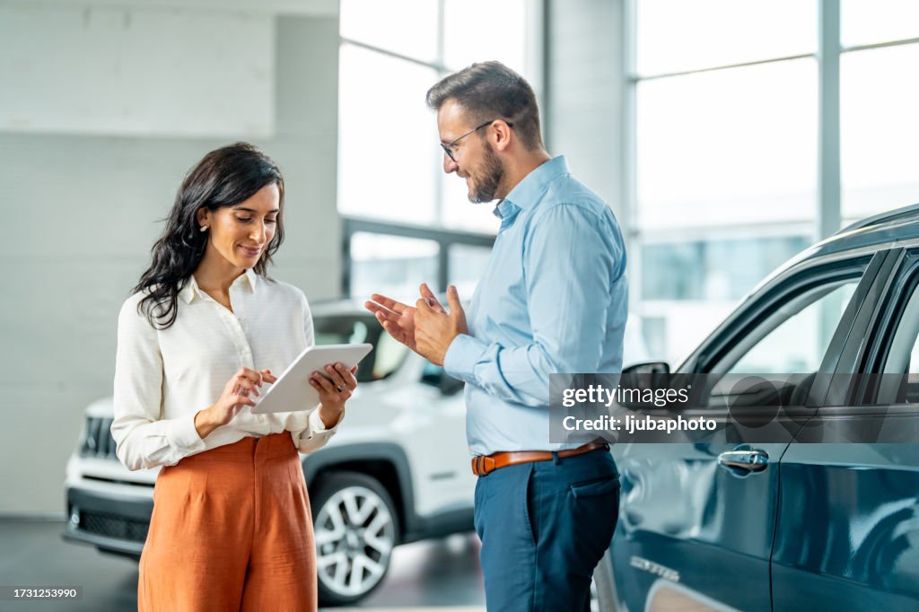 Cliente alegre da concessionária de automóveis conversando com consultor de vendas de automóveis