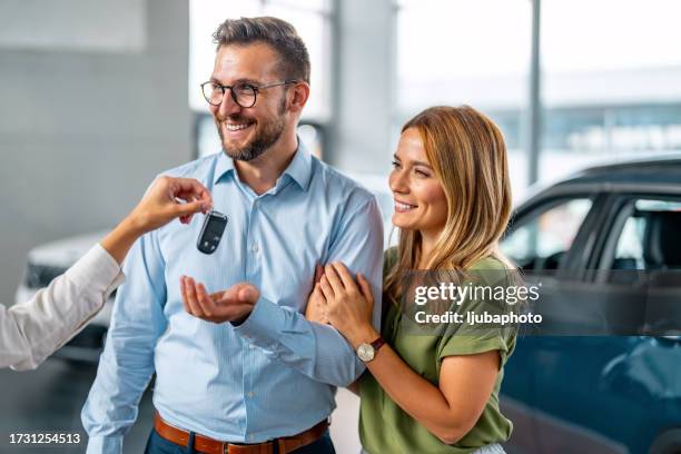 cheerful couple buying car in modern salon - new stock pictures, royalty-free photos & images