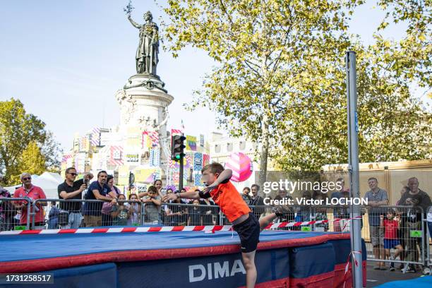 Enfant s'essayant au saut en hauteur en Fosbury-flop paralympique à la journée paralympique le 8 octobre 2023 Place de la République à Paris.