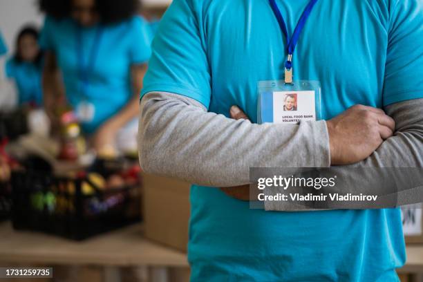 unkenntlicher mann mit verschränkten armen - essensausgabe stock-fotos und bilder