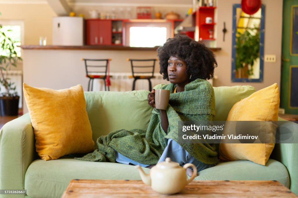 Woman encased in a blanket, with a hot drink
