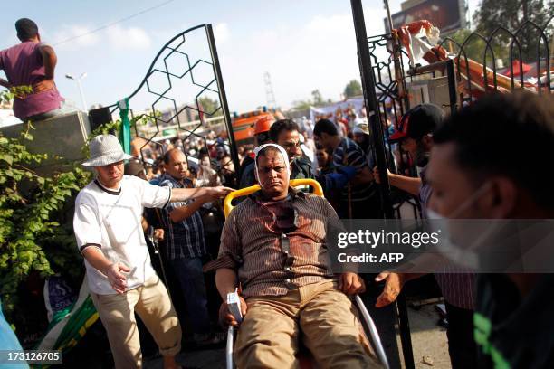 Injured man is wheeled into a make shift hospital where victims are being brought following clashes between Egyptian police and Muslim Brotherhood...