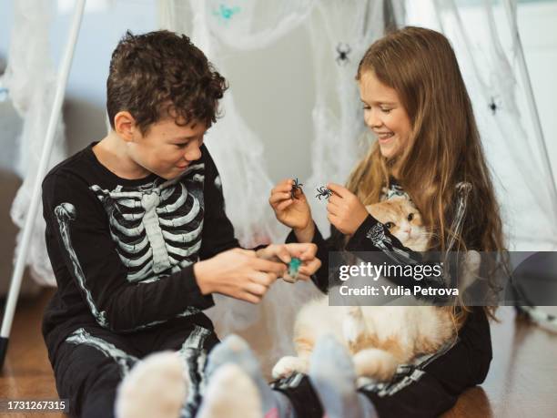 halloween kids in skeleton outfits with a cat - cat skeleton 個照片及圖片檔