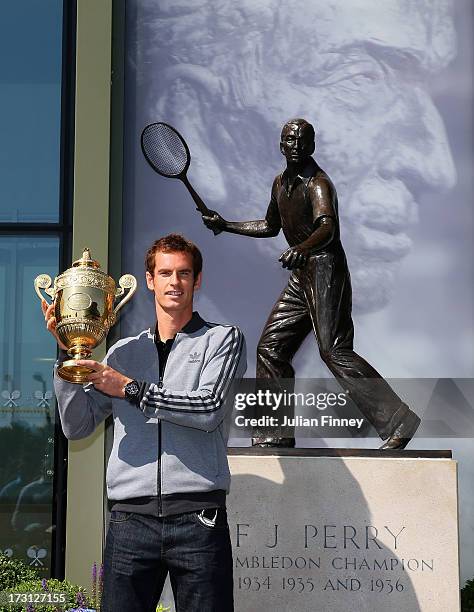 Andy Murray of Great Britain poses with the Gentlemen's Singles Trophy next to the Fred Perry statue at Wimbledon on July 8, 2013 in London, England.