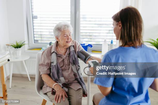 doctor measuring elderly patient's blood pressure in doctor office. - cardiopulmonary system stock pictures, royalty-free photos & images