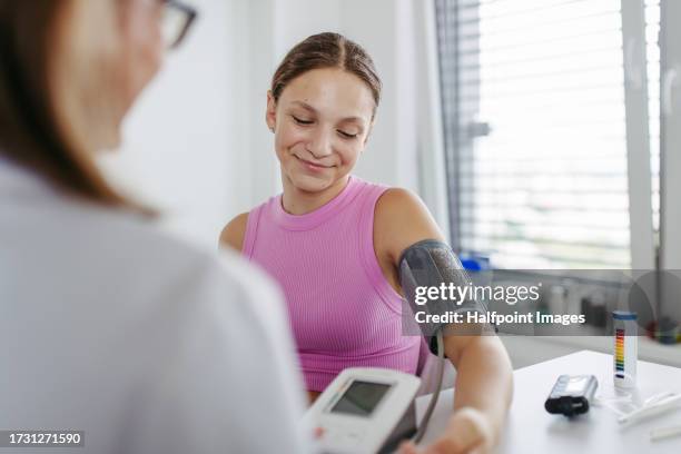 doctor measuring a patient's blood pressure in clinic. - bloeddrukmeter stockfoto's en -beelden