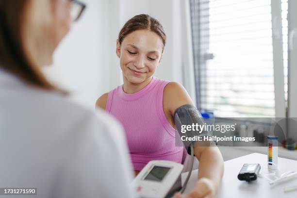 doctor measuring a patient's blood pressure in clinic. - prophylaxie stock pictures, royalty-free photos & images