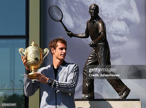 Andy Murray of Great Britain poses with the Gentlemen's Singles Trophy next to the Fred Perry statue at Wimbledon on July 8, 2013 in London, England.