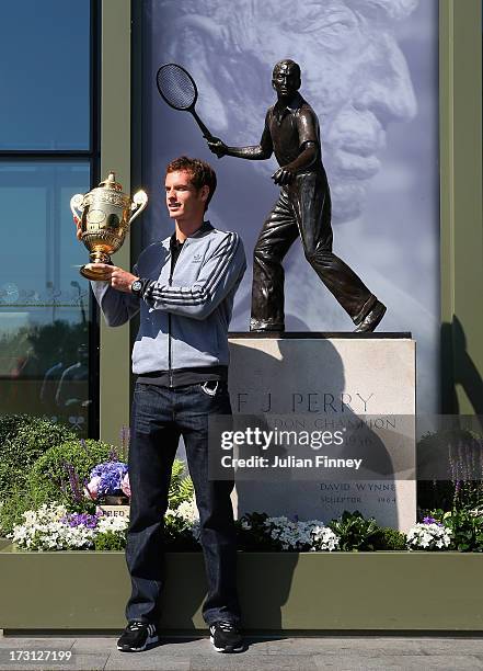 Andy Murray of Great Britain poses with the Gentlemen's Singles Trophy next to the Fred Perry statue at Wimbledon on July 8, 2013 in London, England.