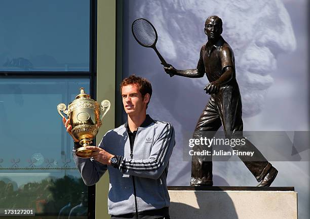 Andy Murray of Great Britain poses with the Gentlemen's Singles Trophy next to the Fred Perry statue at Wimbledon on July 8, 2013 in London, England.