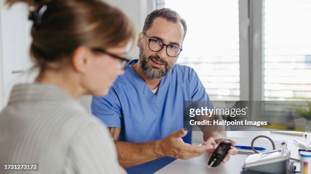 diabetologist doctor testing blood sample on blood sugar meter in diabetes clinic. - diabetes symptoms stock pictures, royalty-free photos & images