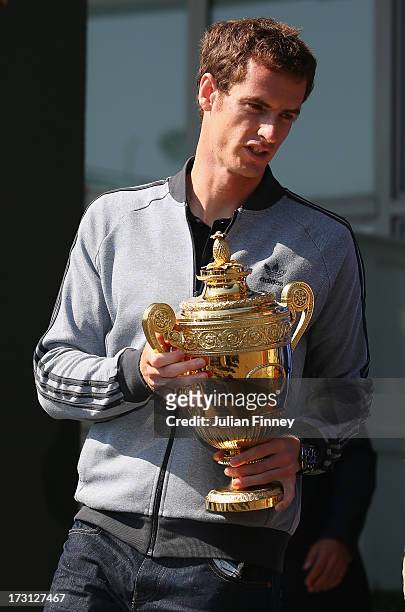 Andy Murray of Great Britain arrives with the trophy before posing with the Gentlemen's Singles Trophy next to the Fred Perry statue at Wimbledon on...
