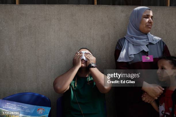 Man reacts alongside a woman and child after seeing the body of a family member, allegedly killed during a shooting at the site of a pro-Morsi sit-in...