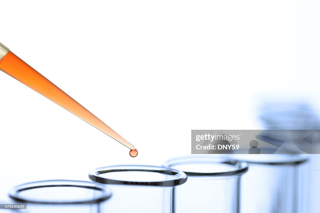 Scientist using pipette to drop a solution into a test tube