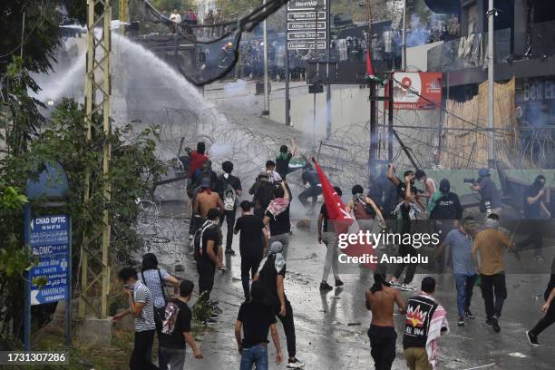 Security forces spray pressurized water as people, carrying the Palestinian flags, gather in front of the US Embassy to protest against the Israeli...