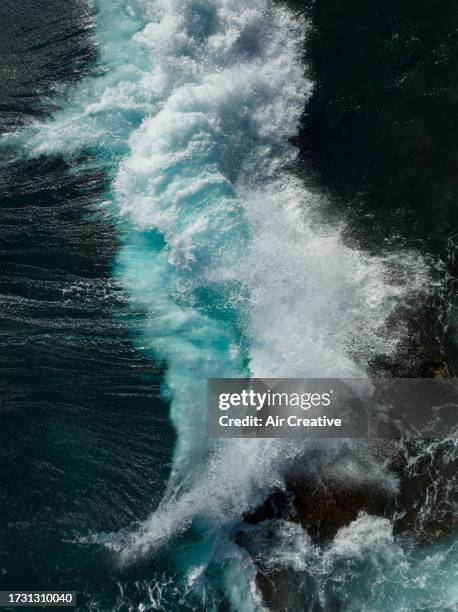 drone image of waves breaking on the coastline during a strong wind day - air waves stockfoto's en -beelden