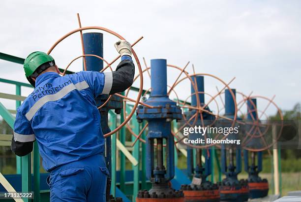 Worker adjusts a valve wheel on pipework at an oil plant operated by Salym Petroleum in Salym, Khanty-Mansi autonomous region, Russia, on Wednesday,...