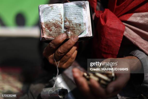 An Egyptian supporter of deposed president Mohamed Morsi holds a copy of the Koran stained with blood and empty casing as he attends a rally in...