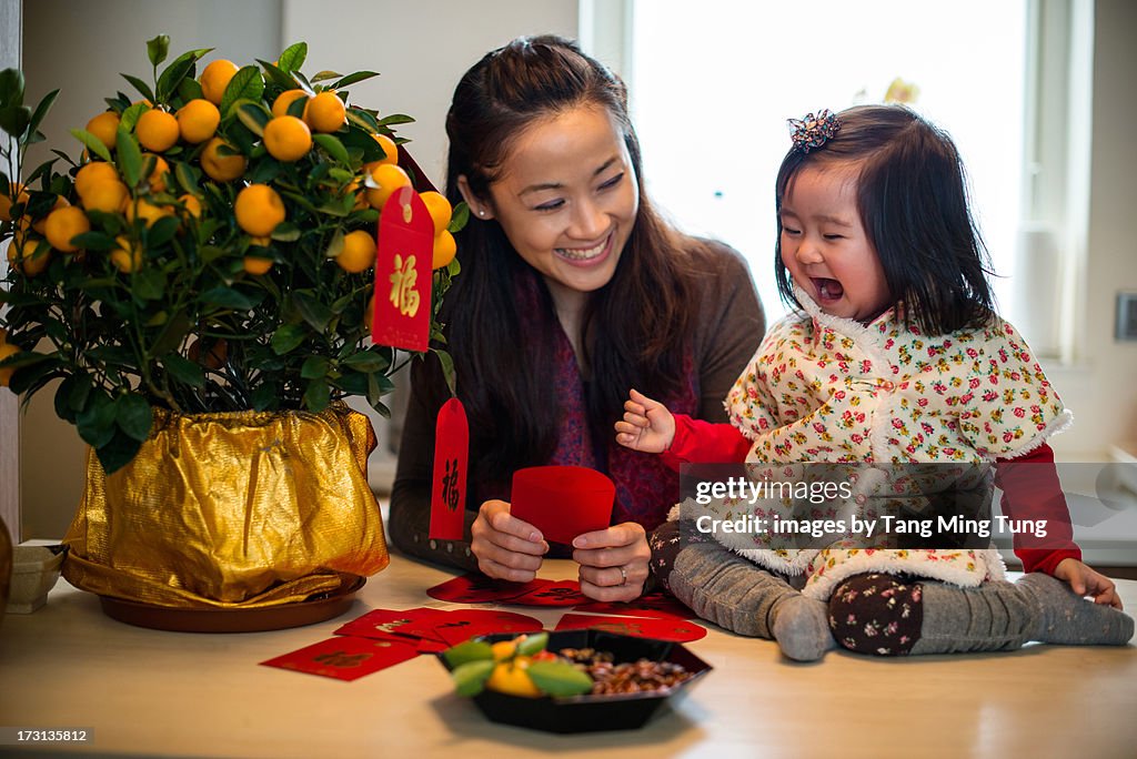 Mom decorating CNY tangerine tree with toddler