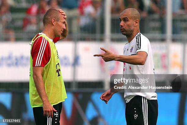 Head coach Josep Guardiola of FC Bayern Muenchen talks to his player Arjen Robben during a training session at Campo Sportivo on July 8, 2013 in...