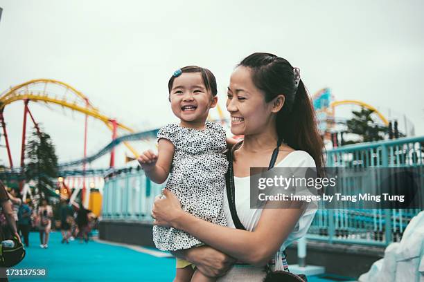 mom holding toddler in amusement park joyfully - amusement park sky stock pictures, royalty-free photos & images