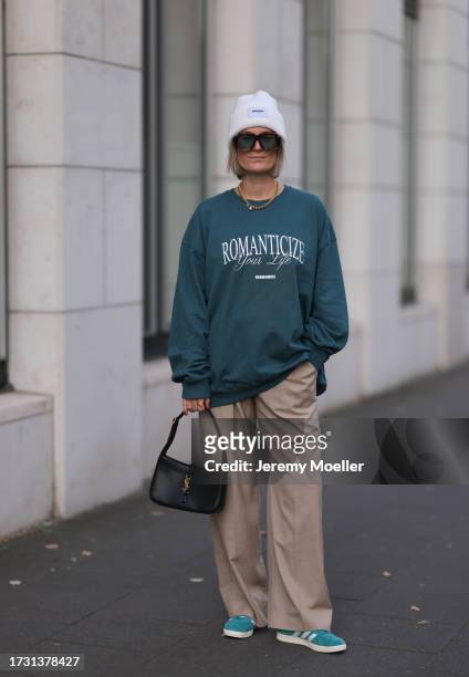 Victoria Thomas is seen wearing a white beanie from Hernameis the label, large sunglasses with havana frame and blue lenses from Loewe, golden chunky...