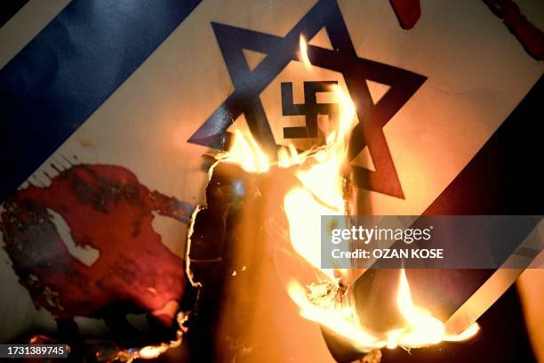 This photograph taken on October 18 shows a placard representing a flag of Israel with a Nazi Swastika inside the Star of David, during a rally in...