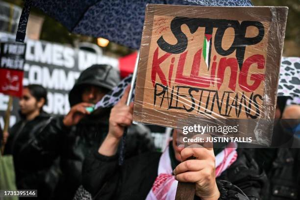 Protester, holding a placard reading a message in support of Palestinians, take part in a vigil outside Downing Street, in London, on October 18,...
