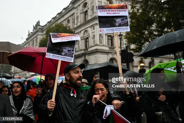 Protesters, holding placards reading messages in support of Palestinians, take part in a vigil outside Downing Street, in London, on October 18, 2023...