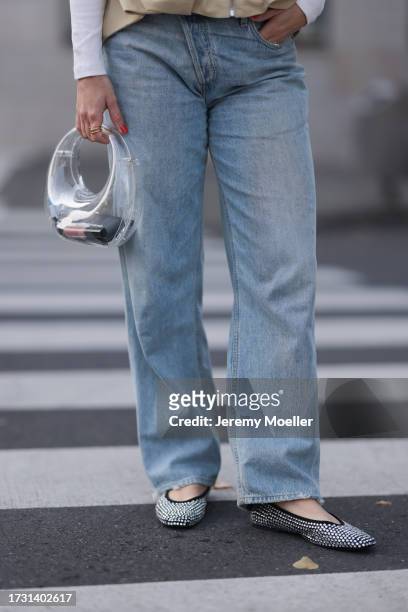 Victoria Thomas is seen wearing light blue jeans with straight leg from Agolde, a transparent bag from Mango and black ballet flats covered with...