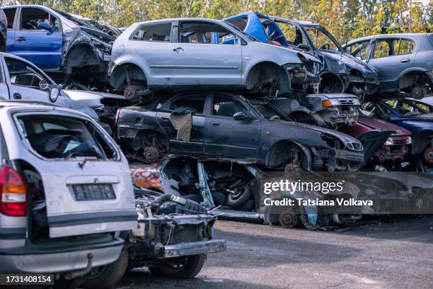 rows of car bodies, stripped of wheels and interior, rest almost intact on top of each other in recycling facility - messy car interior stock pictures, royalty-free photos & images