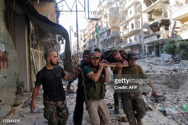 Opposition fighters carry one of their comrades, who died on the front-line, as they were leading an attack on positions held by the Syrian...