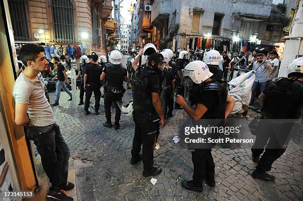 Turkish police pause as they chase anti-government protestors along the Istiklal shopping street near Taksim Square on July 8, 2013 in Istanbul,...