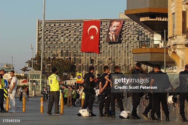 Turkish riot police line up in Taksim Square in front of a building with a Turkish flag and portrait of the founder of modern Turkey, Mustafa Kemal...