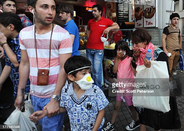 Family covers their faces because of tear gas, as Turkish police battle anti-government protestors along the Istiklal shopping street near Taksim...