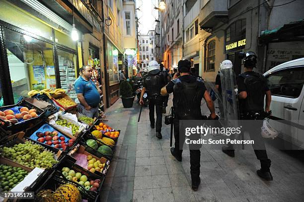 Turkish police pass a fruit stand, as they chase anti-government protestors along the Istiklal shopping area near Taksim Square on July 8, 2013 in...