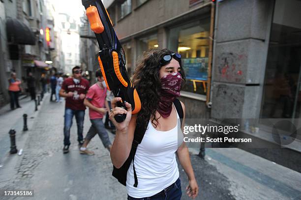 Woman protestor holds a large squirt gun to parody water cannons used by police, as Turkish police battle anti-government protestors along the...